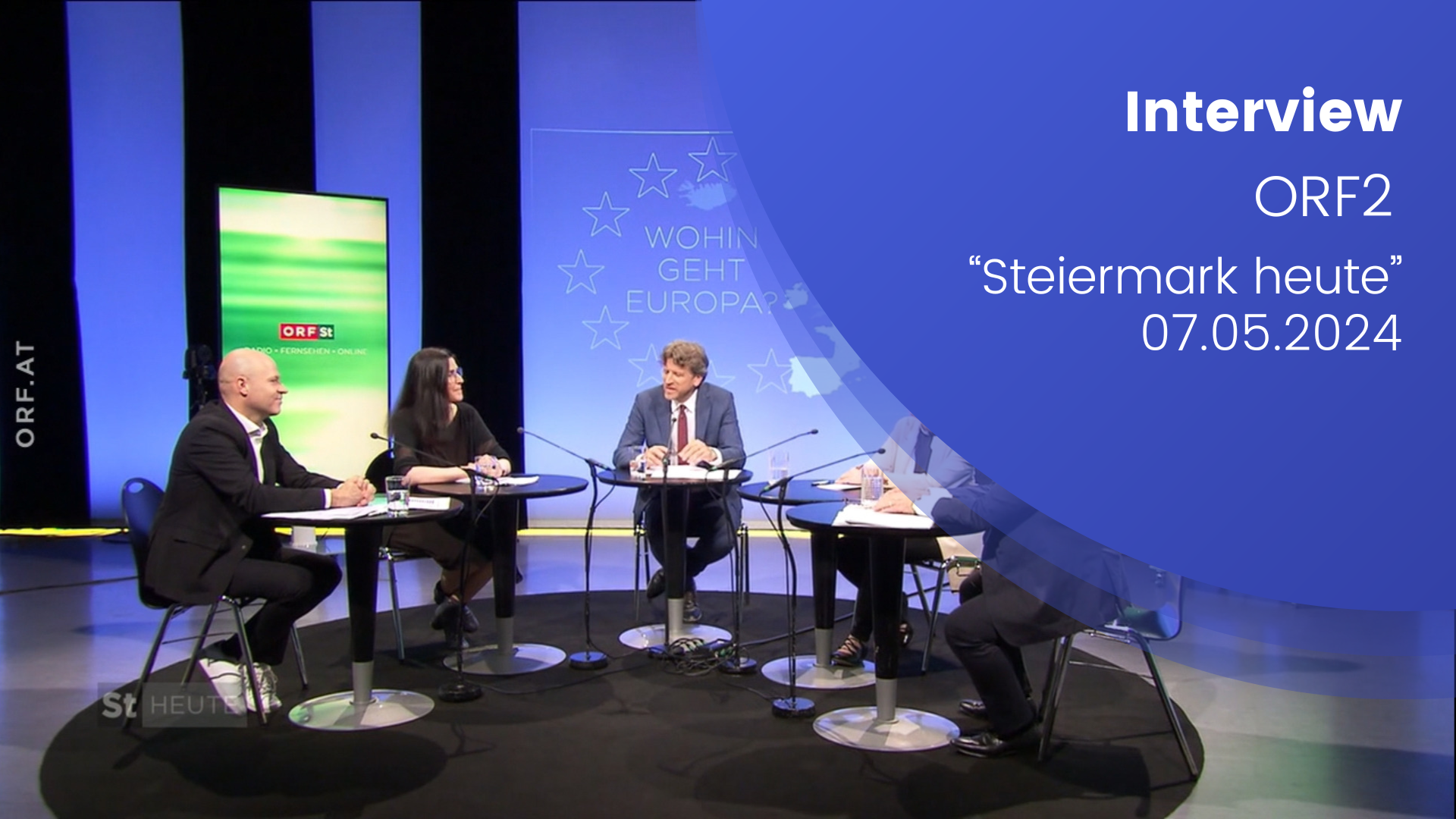 Paul Schmidt ist in Steiermark heute in einer Diskussionsrunde zu sehen. Die Panel Diskutant:innen sitzen um einen Tisch, im Hintergrund ist ein digitaler Banner mit der STeiermark heute Aufschrift und grünem Hintergrund. Rechts ist ein Text übergelegt auf blauem Hintergrund: Interview ORF 2, Steiermark heute, 07.05.2024".